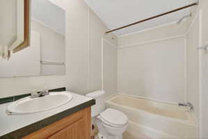 Full bathroom featuring a single vanity with wood-finish cabinetry, a white oval sink, and a built-in bathtub with shower