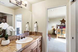 Vanity featuring a stone countertop, an undermount sink, and a bronze-finish faucet