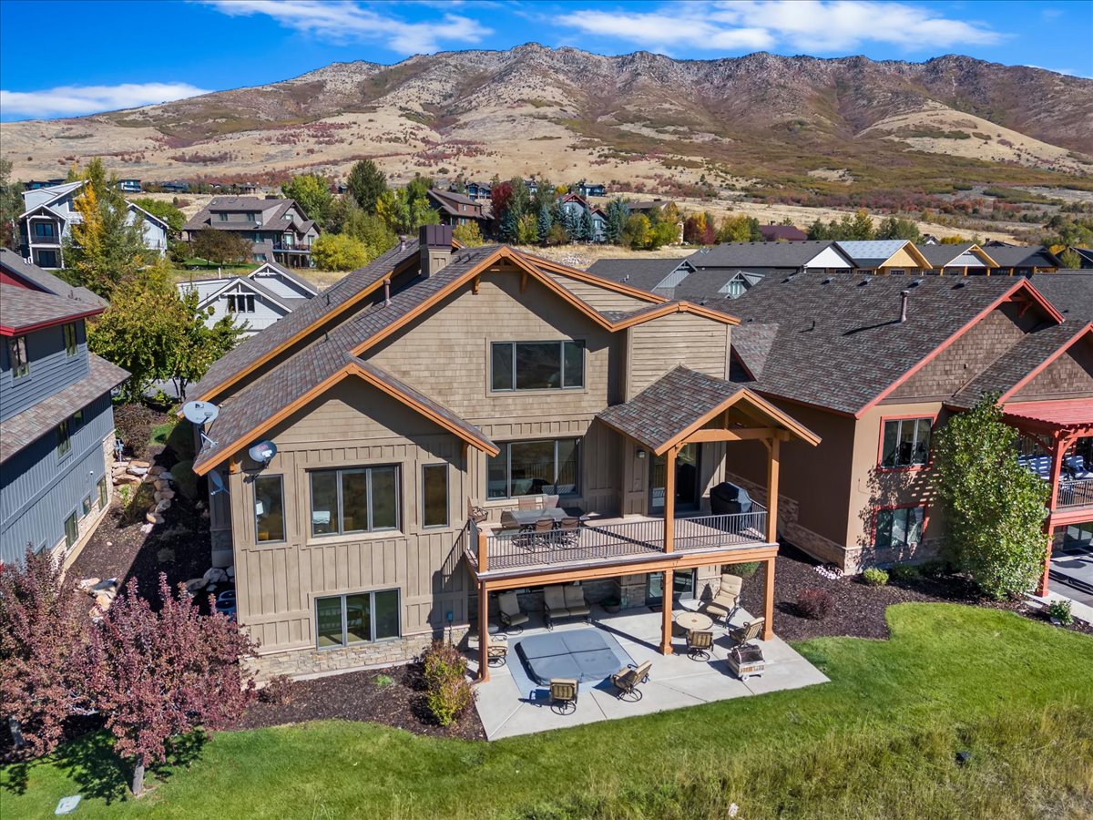 Multi-level residence featuring a spacious deck with covered porch, lower patio, and a grass lawn area