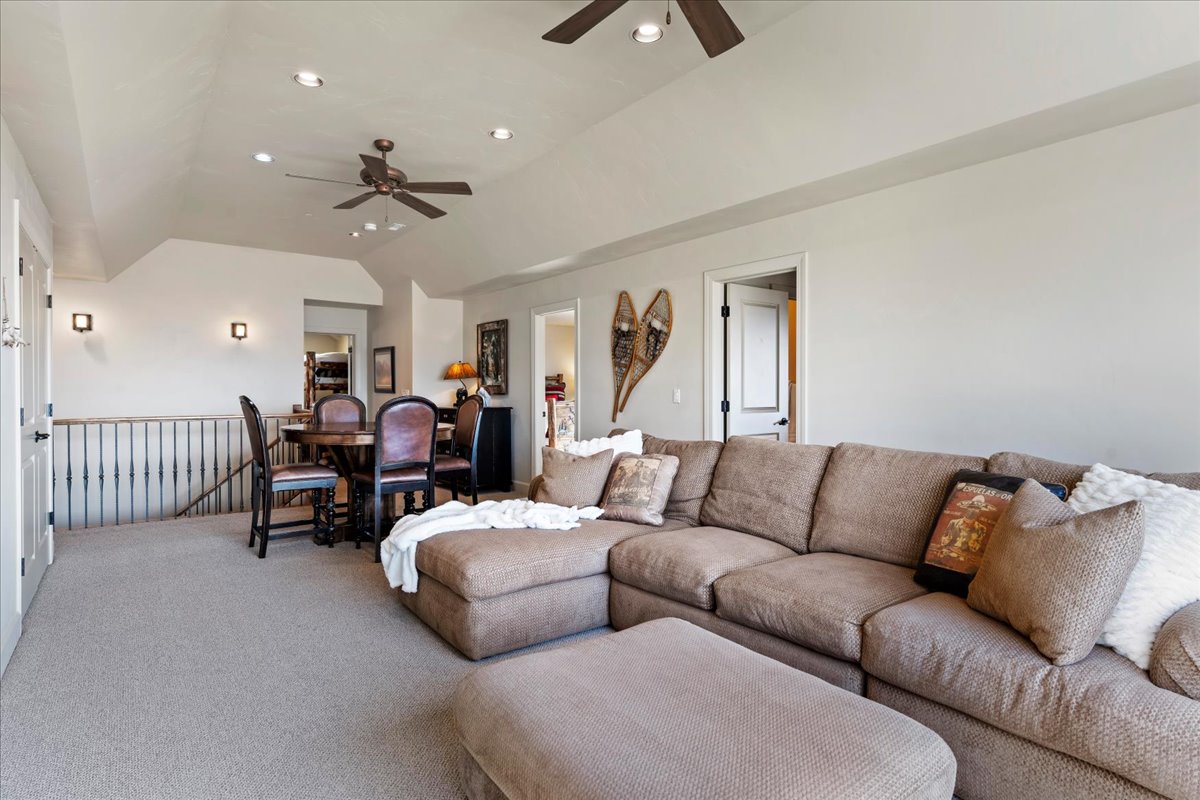 Spacious upper-level room featuring vaulted ceilings, recessed lighting, and light-colored carpeting