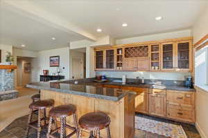 Wet bar with a granite countertop, undermount sink, and wood-finish cabinetry featuring glass-paneled doors and a wine rack
