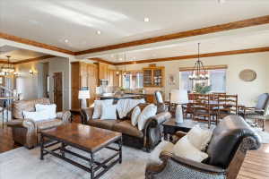 Open-concept living area featuring exposed wood beams, wood-finish flooring, recessed lighting, and a built-in kitchen with wood cabinetry