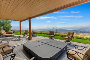 Expansive covered patio featuring a hot tub, composite decking, and a concrete patio area