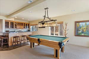 Recreational space with a built-in wet bar featuring upper and lower cabinetry, a stone countertop, and a built-in wine rack