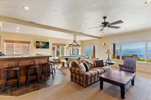 Entertainment space featuring a wood-panel wet bar with stone-finish countertop, recessed lighting, and a ceiling fan