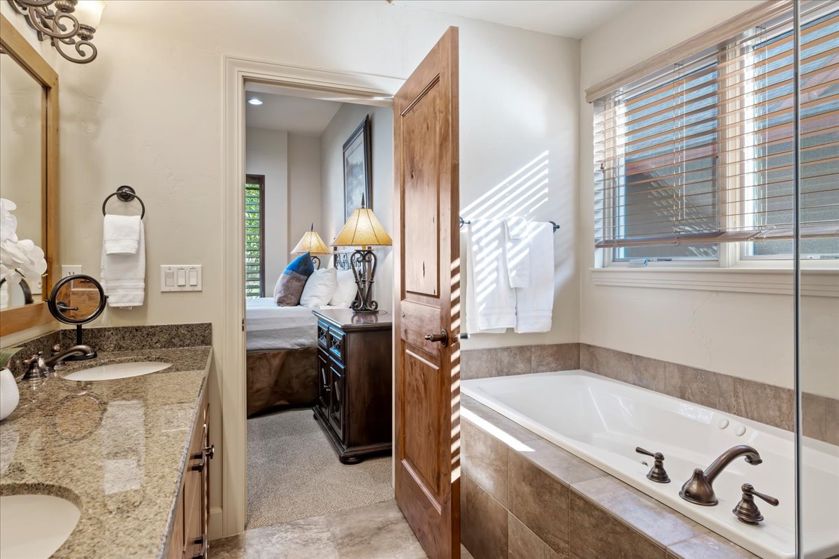 Bathroom featuring a double vanity with stone countertops, an undermount sink, and a framed mirror