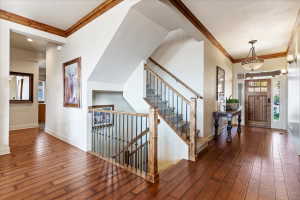 Hardwood flooring throughout the entryway featuring a multi-level staircase with wood railings and metal balusters