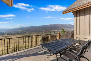Expansive outdoor patio featuring stamped concrete flooring, dark metal railing, and a mountainous landscape
