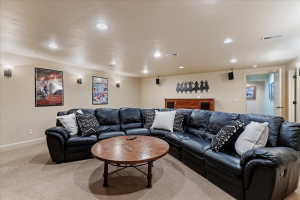 Spacious entertainment room featuring recessed ceiling lighting, wall-mounted sconces, and neutral carpeting