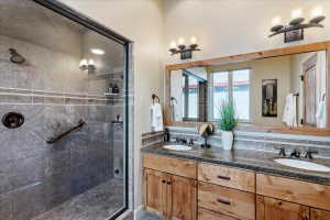 Spacious bathroom featuring a dual vanity with a granite countertop, wood-finish cabinetry, and a large framed mirror