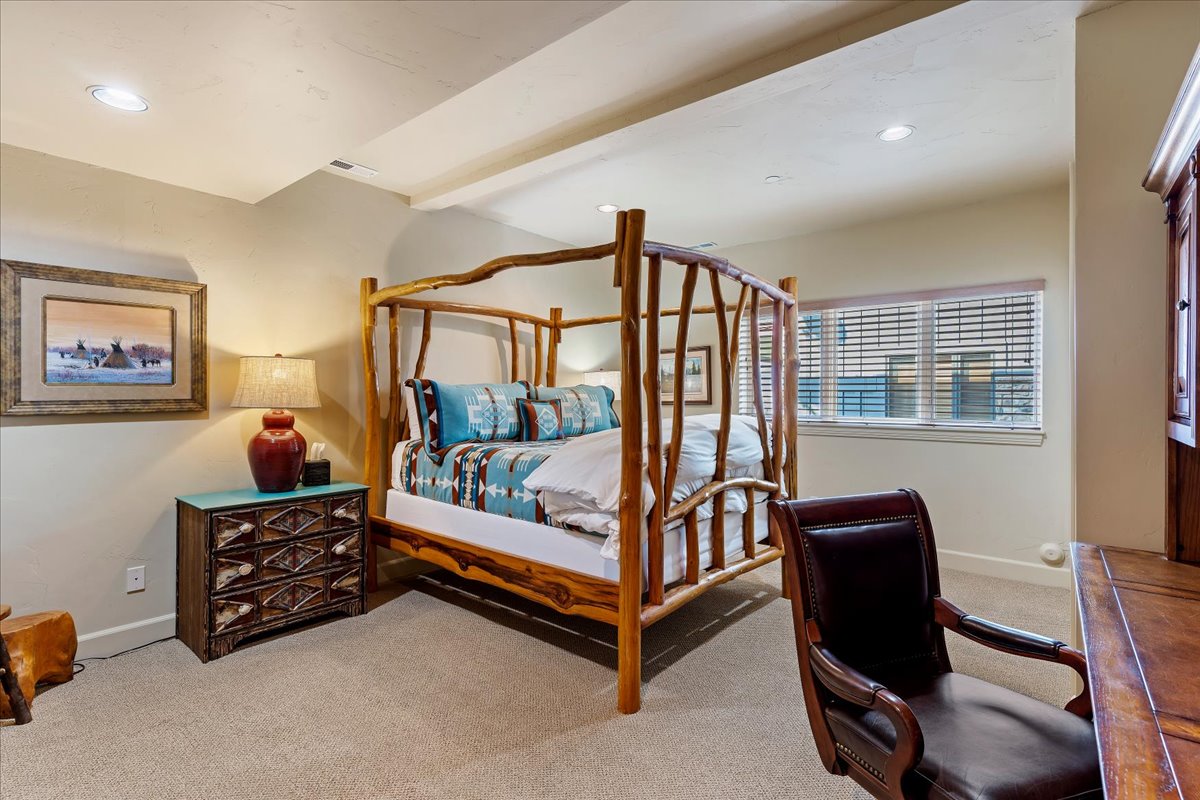 Carpeted bedroom featuring a rustic wood-frame bed, recessed lighting, and a window with horizontal blinds