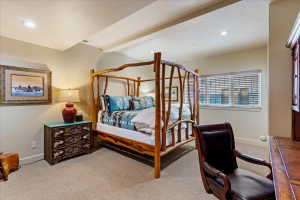 Carpeted bedroom featuring a rustic wood-frame bed, recessed lighting, and a window with horizontal blinds