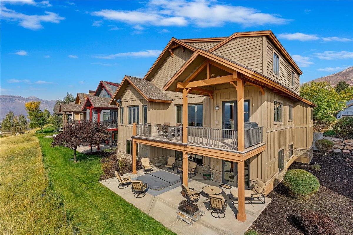 Multi-level siding exterior featuring an upper deck with metal railings and a lower patio