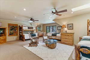 Spacious room featuring multiple sleeping areas, recessed lighting, two ceiling fans, and a skylight