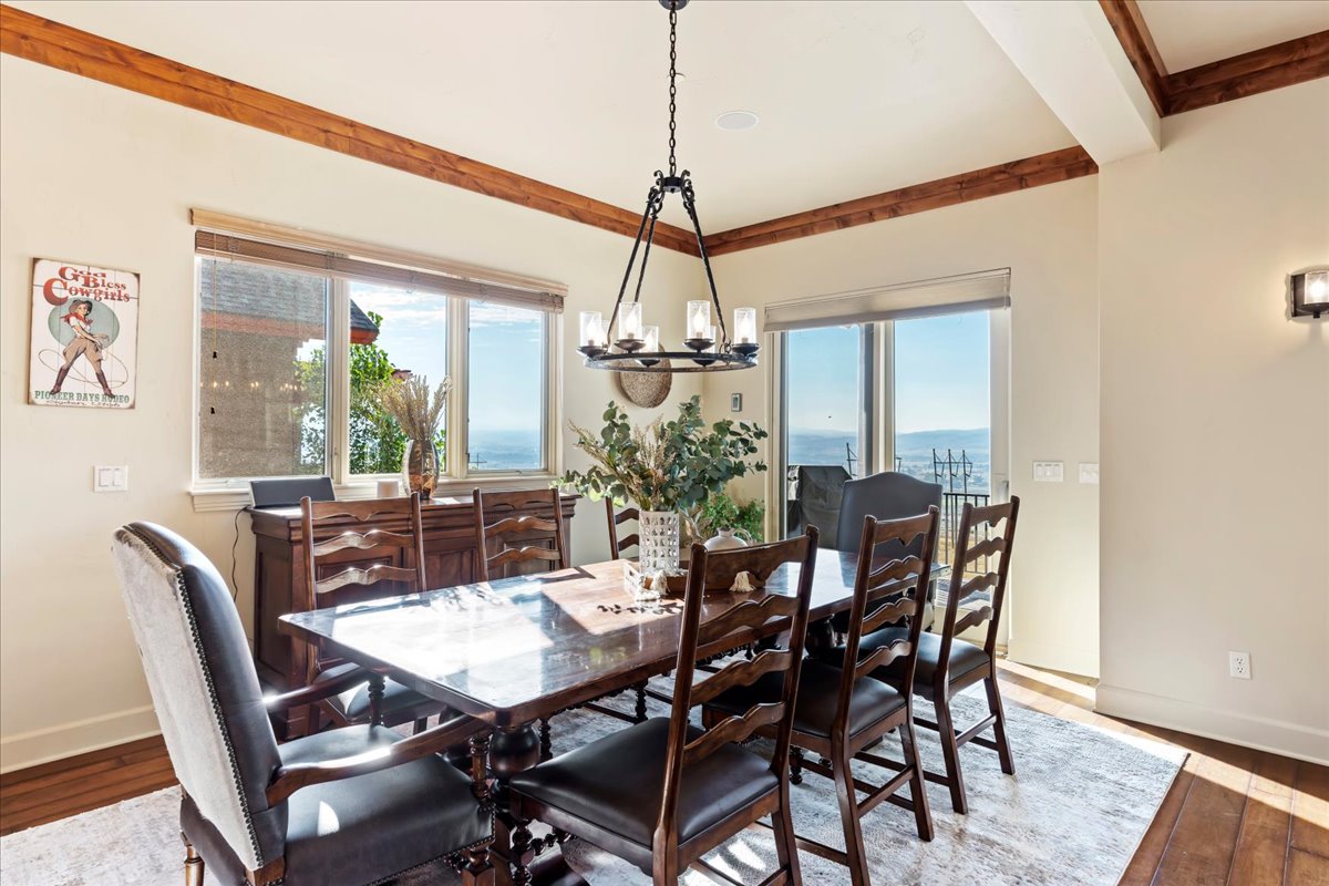 Dining area featuring wood-finish flooring, exposed ceiling beams, and a chandelier