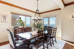 Dining area featuring wood-finish flooring, exposed ceiling beams, and a chandelier
