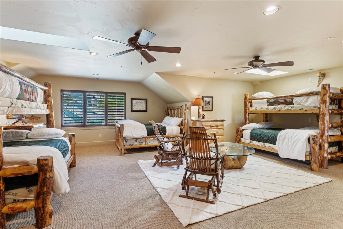 Spacious bedroom featuring neutral carpeting, multiple ceiling fans, and sloped ceilings with recessed lighting