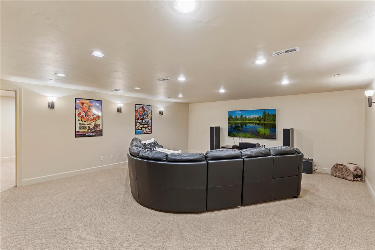 Spacious entertainment room featuring recessed lighting, wall sconces, neutral-toned carpeting, and light-colored walls