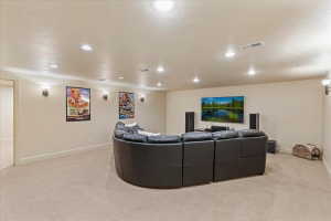 Spacious entertainment room featuring recessed lighting, wall sconces, neutral-toned carpeting, and light-colored walls