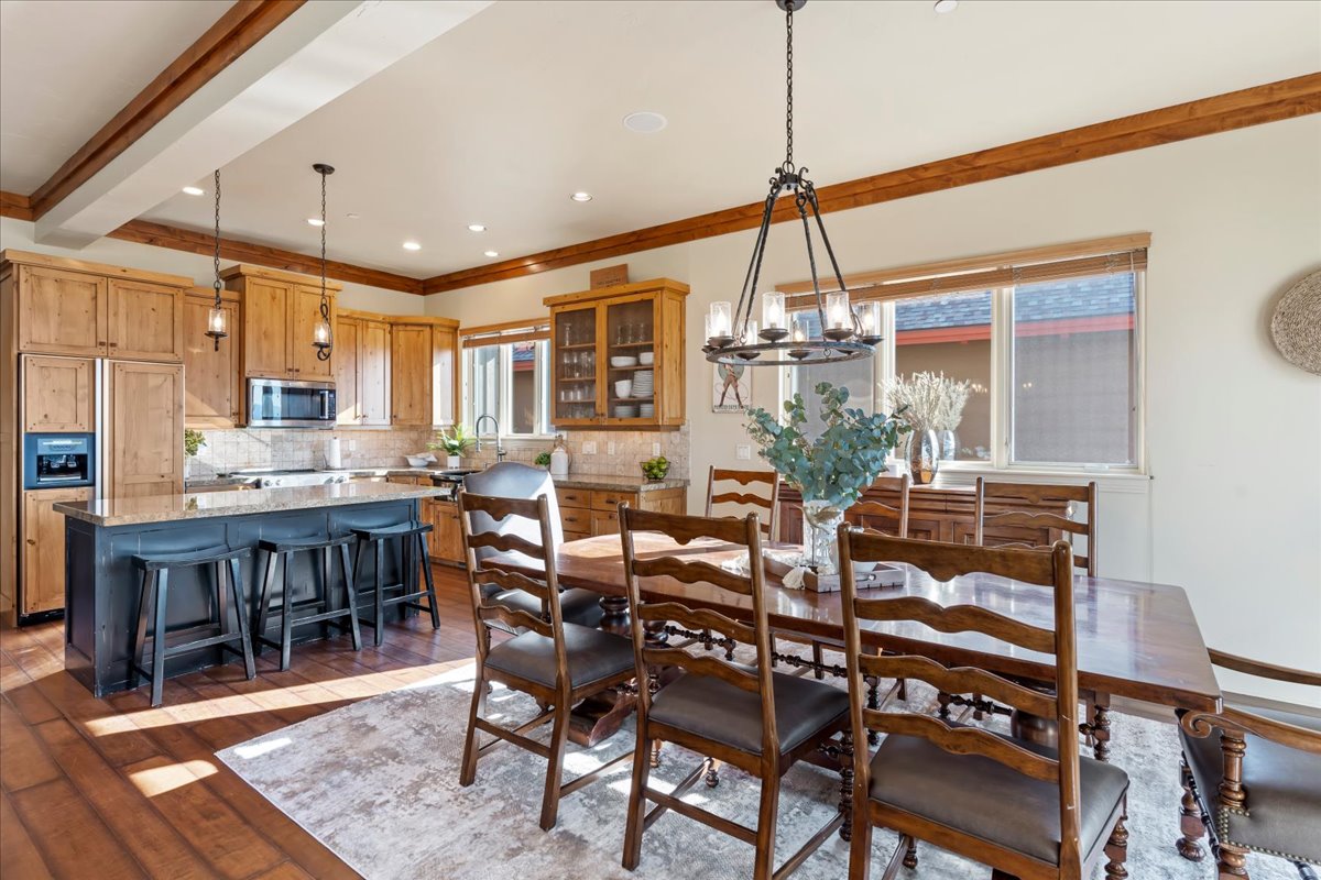 Open-concept kitchen and dining area featuring wood-finish flooring, exposed ceiling beams, and recessed lighting