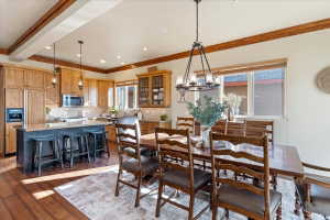 Open-concept kitchen and dining area featuring wood-finish flooring, exposed ceiling beams, and recessed lighting