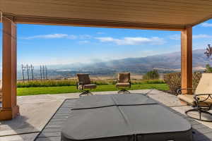 Covered patio featuring a hot tub, concrete paving, and composite decking