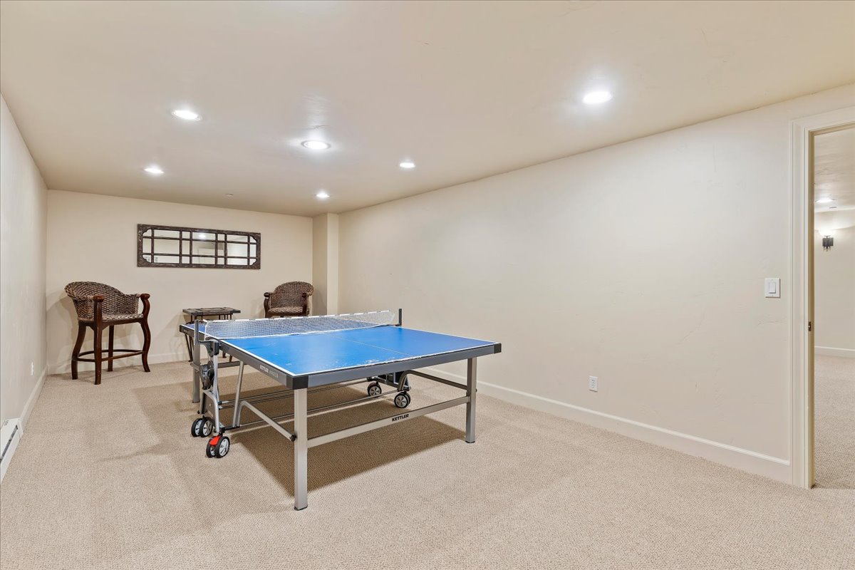 Spacious recreation room featuring recessed lighting, neutral carpeting, and a broad doorway opening into an additional carpeted area
