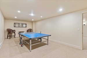 Spacious recreation room featuring recessed lighting, neutral carpeting, and a broad doorway opening into an additional carpeted area