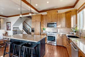 Spacious kitchen featuring natural wood cabinetry, stainless steel appliances, a large island with a stone countertop, recessed lighting, and wood-finish flooring