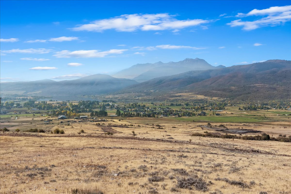 Expansive open terrain with distant mountain ranges and a small community visible in the valley