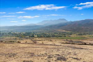 Expansive open terrain with distant mountain ranges and a small community visible in the valley