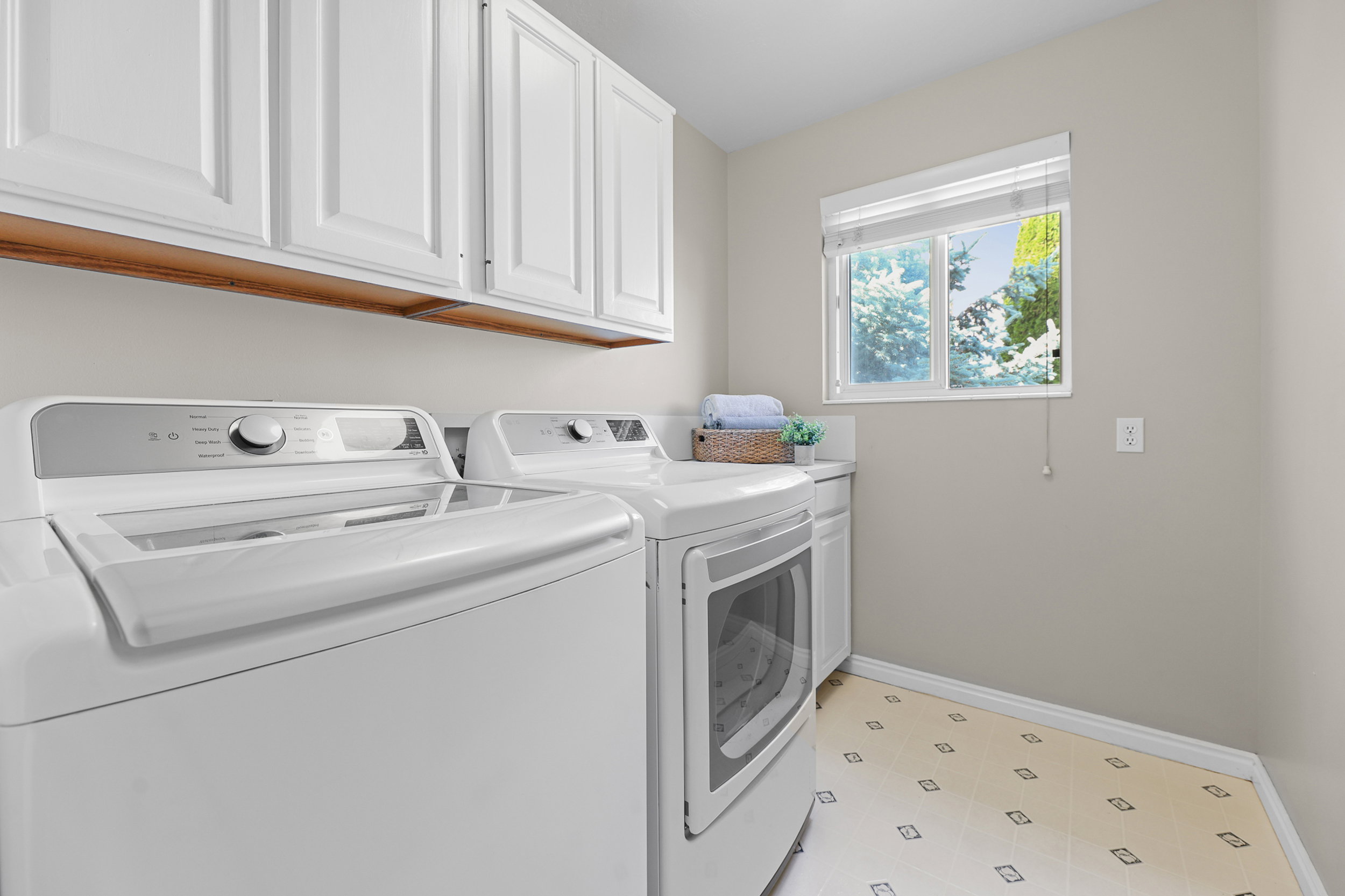 Laundry area featuring white cabinetry, a window, and patterned flooring