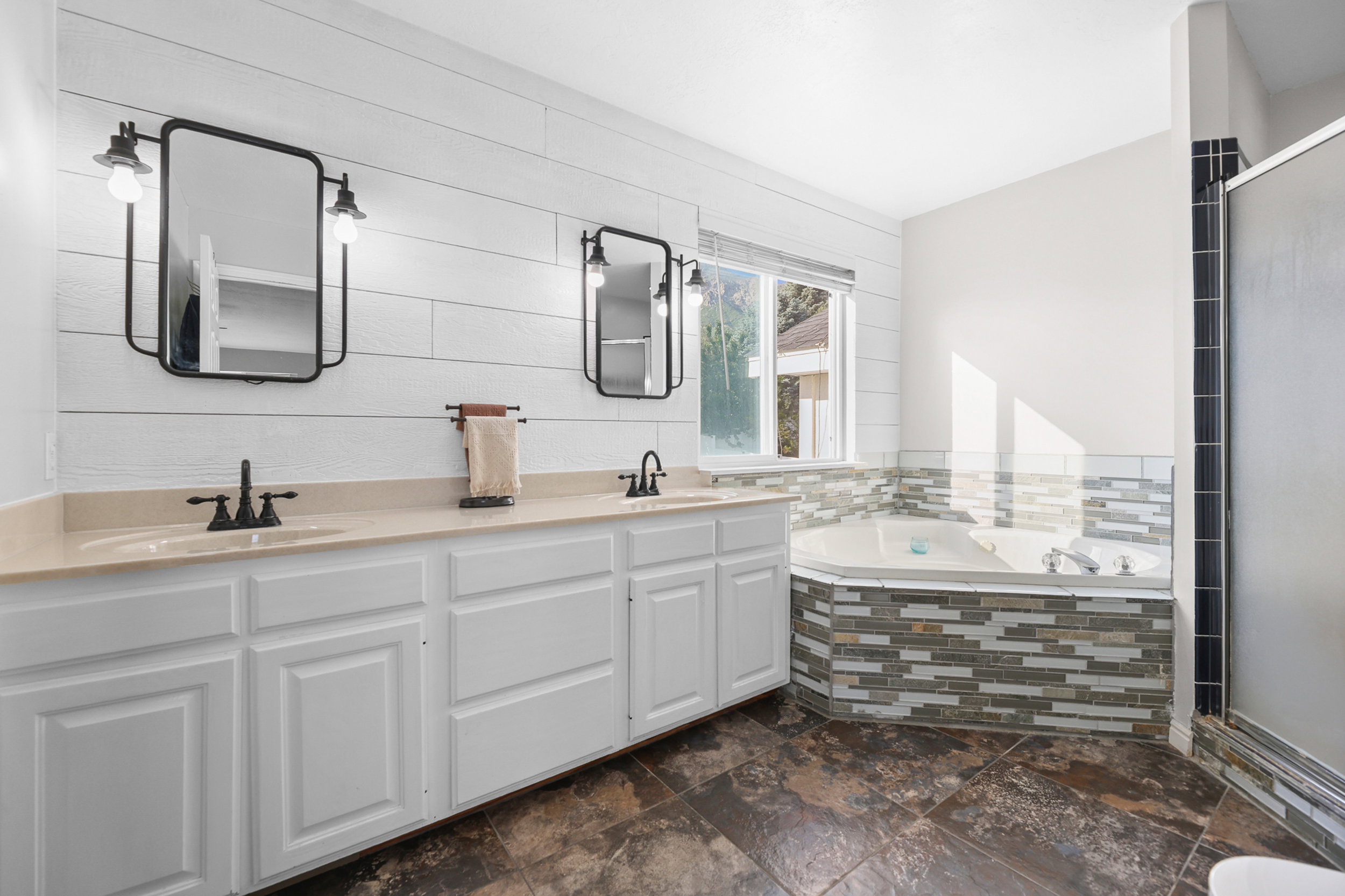Dual sink vanity with light-toned countertops, white cabinetry, and matte black fixtures