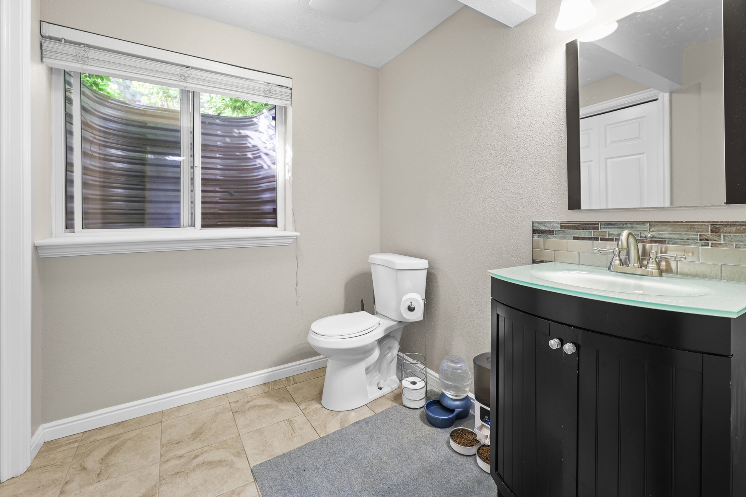 Modern vanity with a clear glass countertop, undermount sink, and brushed nickel faucet