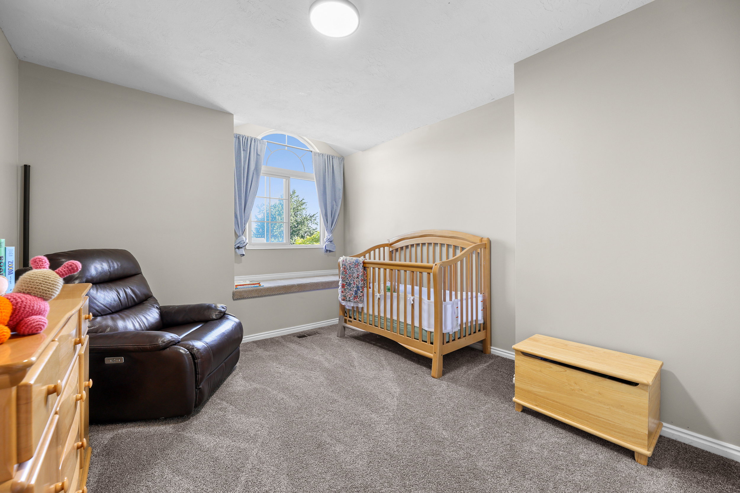 Bedroom featuring neutral wall colors, grey carpet, and a prominent arched window