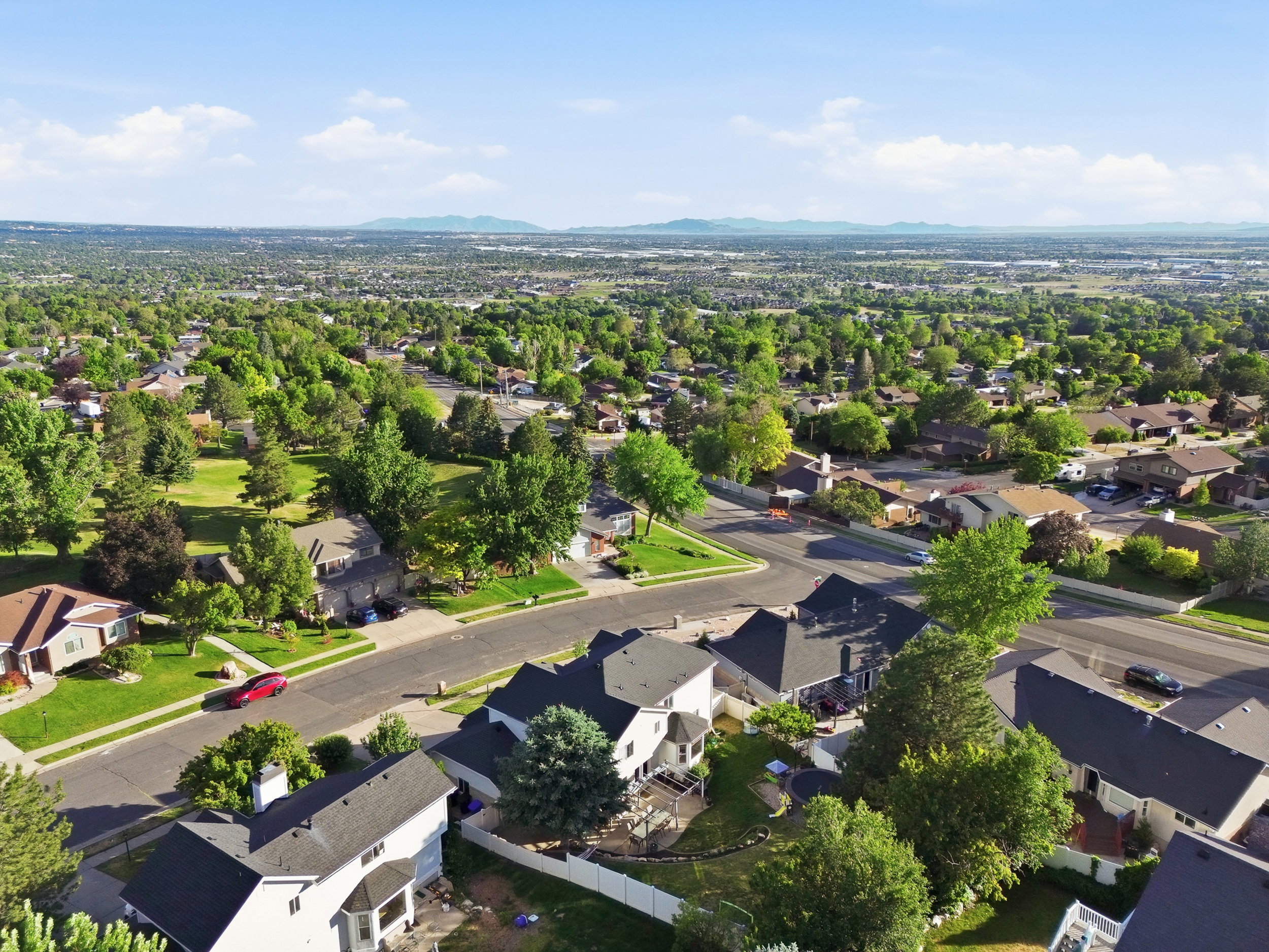 Expansive residential area featuring established homes with dark shingle roofs, mature trees, and green lawns