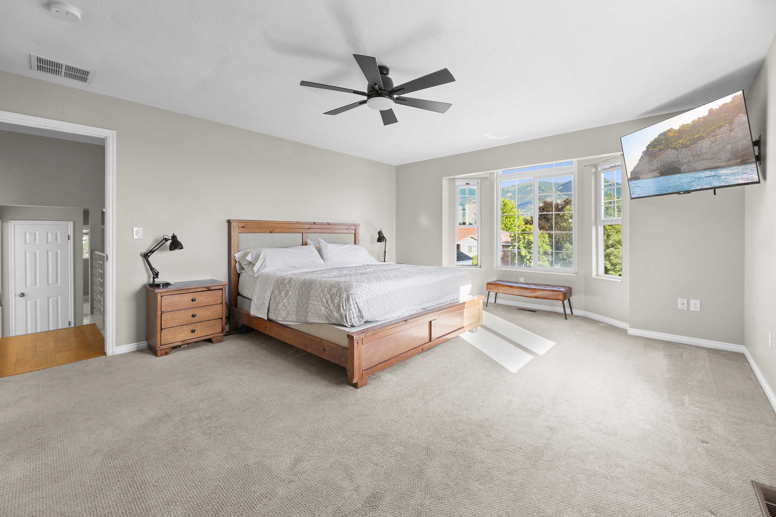Spacious bedroom featuring light neutral wall tones and a textured carpet