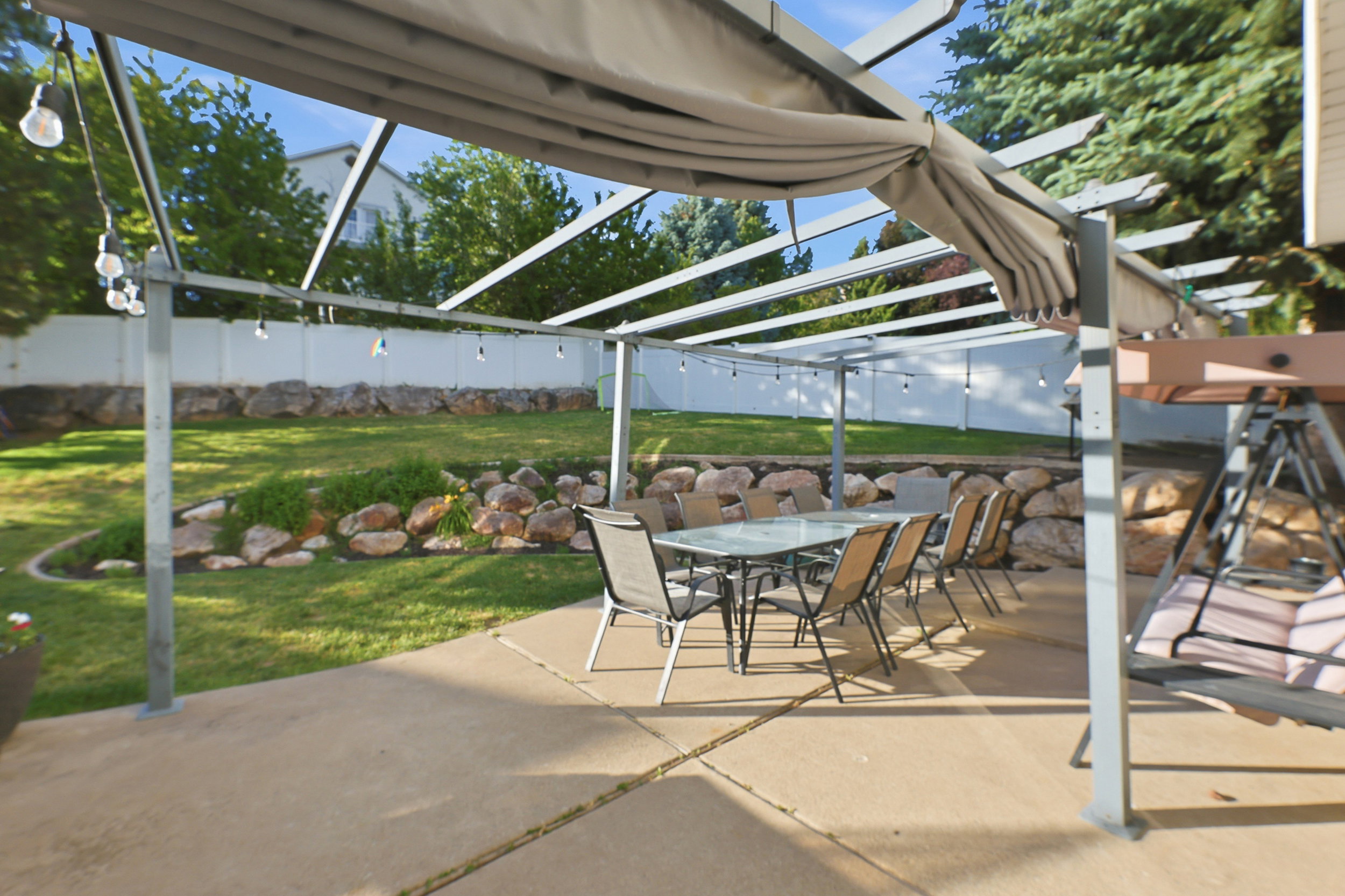 Concrete patio with a pergola structure, string lighting, and a retractable canopy