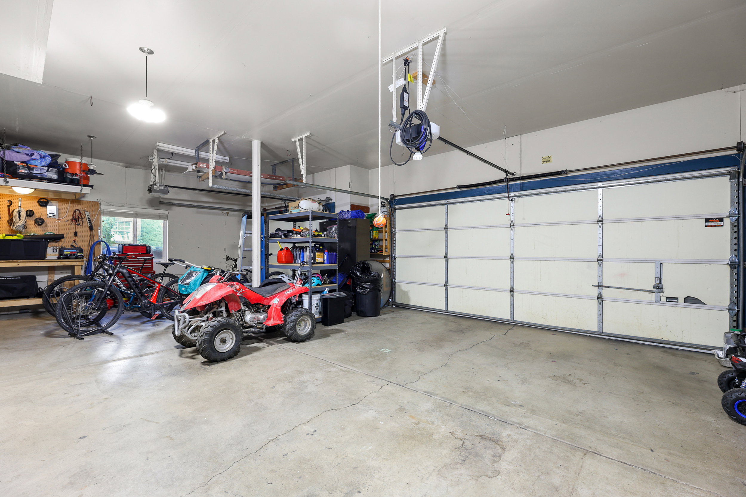 Spacious garage featuring a concrete floor, overhead lighting, and a wide garage door