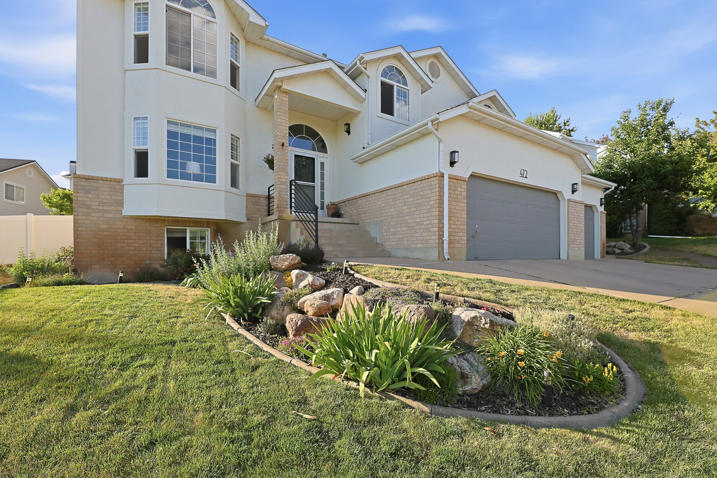 Light-toned stucco exterior with a brick foundation accent