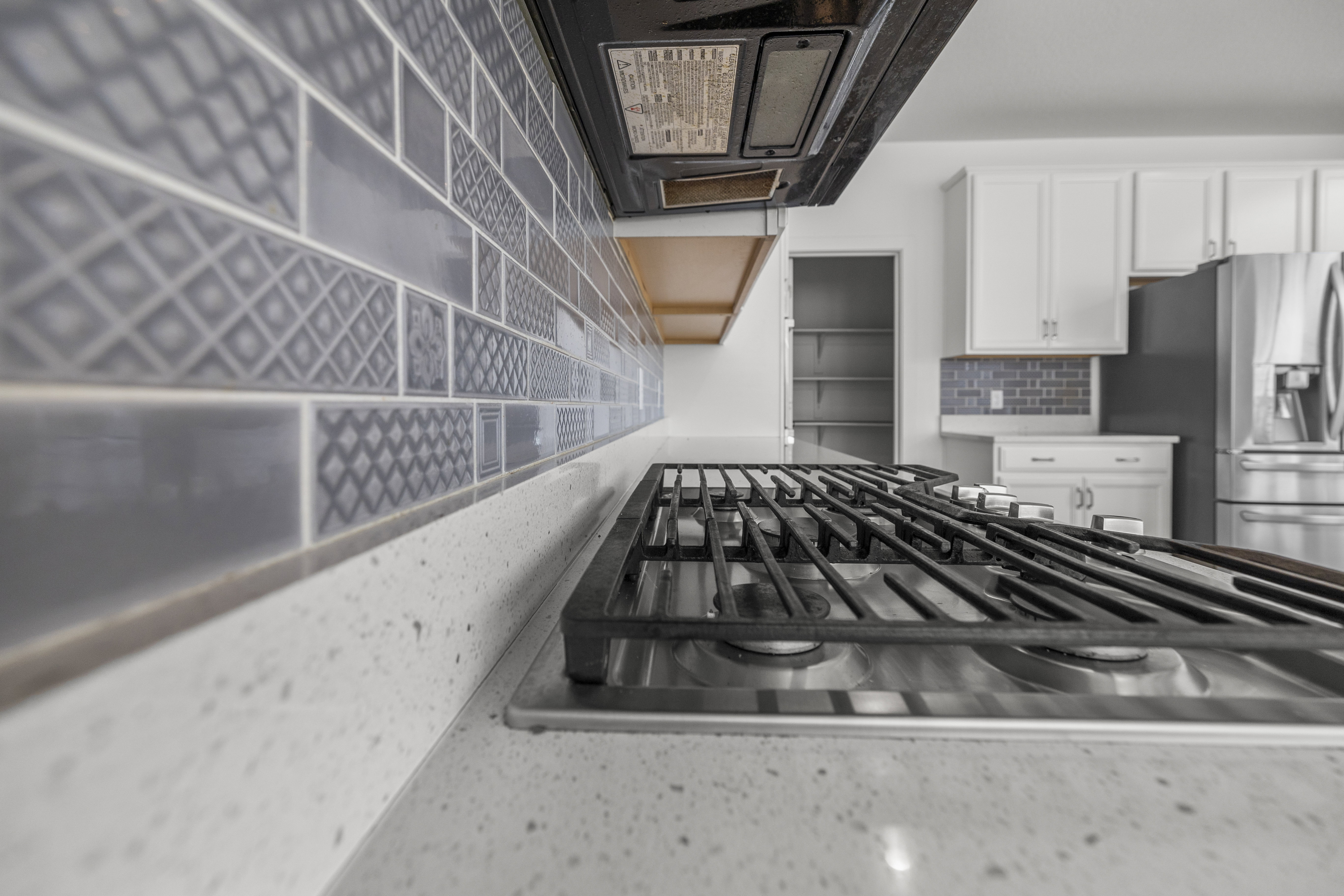 Built-in gas range with stainless steel finish, quartz-finish countertop, and patterned tile backsplash