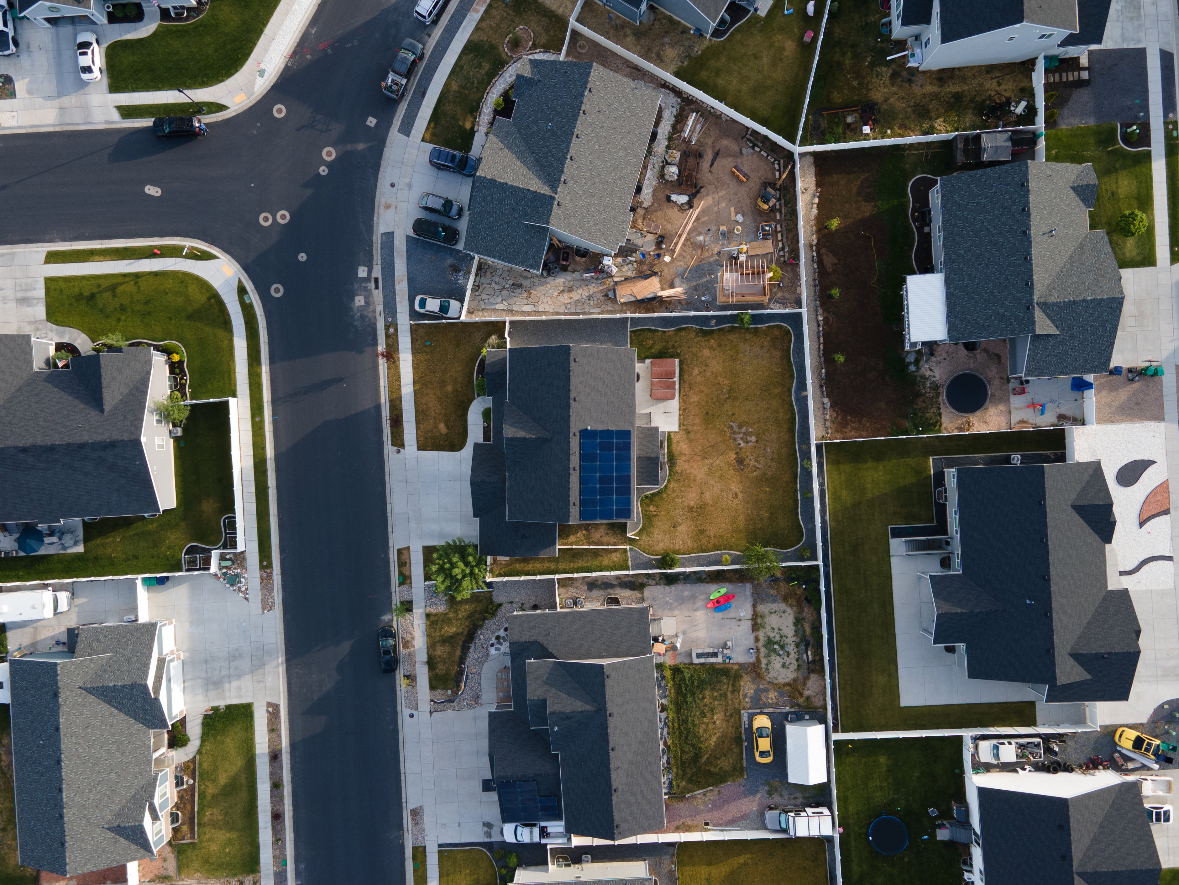 Overhead perspective showcasing a residential property with a dark shingle roof and solar panel array