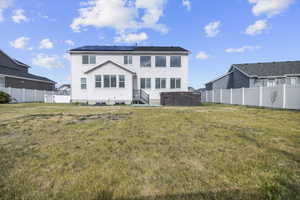Rear exterior featuring white siding, a dark roof, and solar panels
