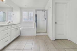 Primary bathroom. Bathroom featuring light-toned tile flooring, a white vanity with a light-colored countertop, and a built-in bathtub with subway tile surround