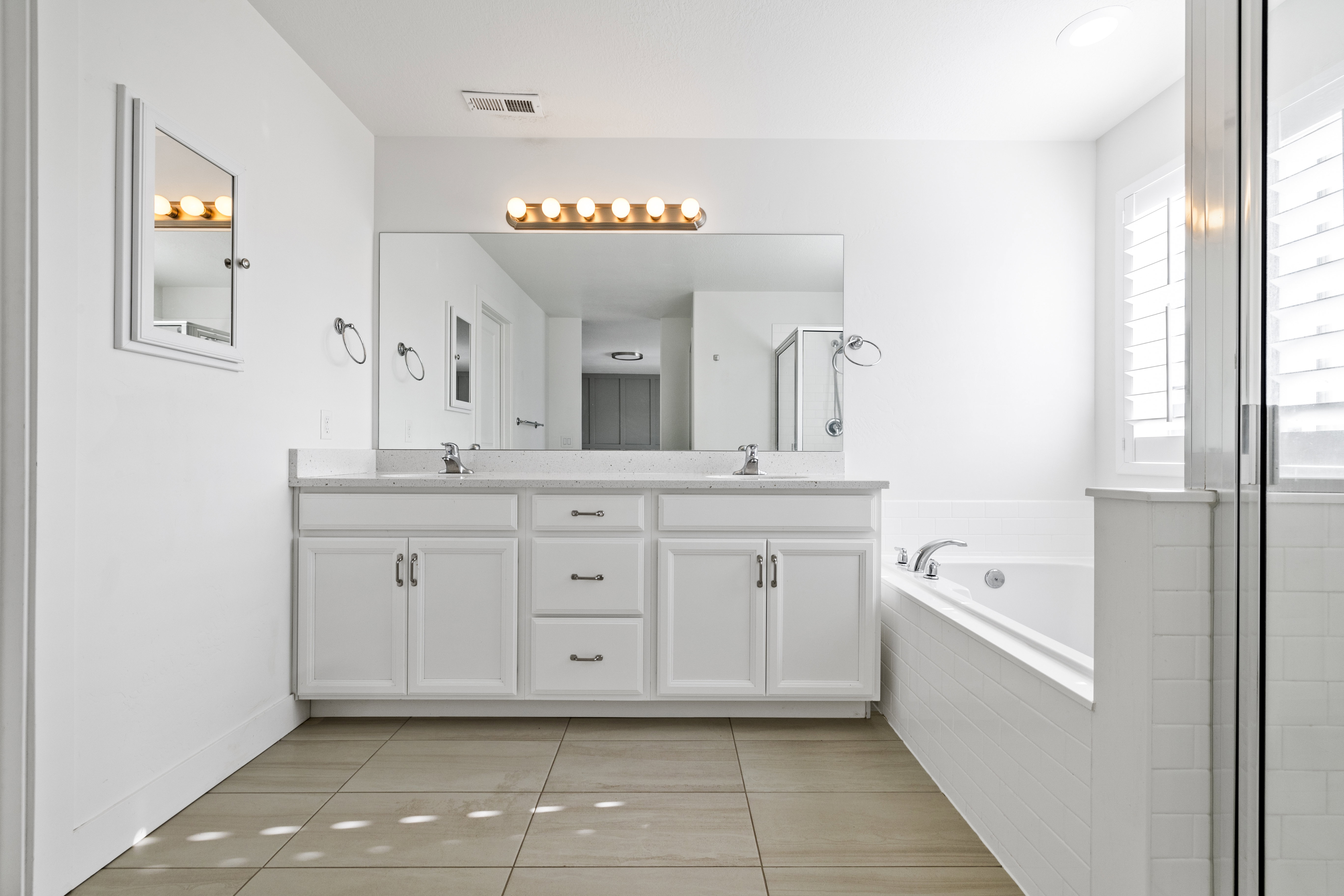 Primary bathroom. Dual vanity with white cabinetry, integrated sinks, and a light-toned countertop