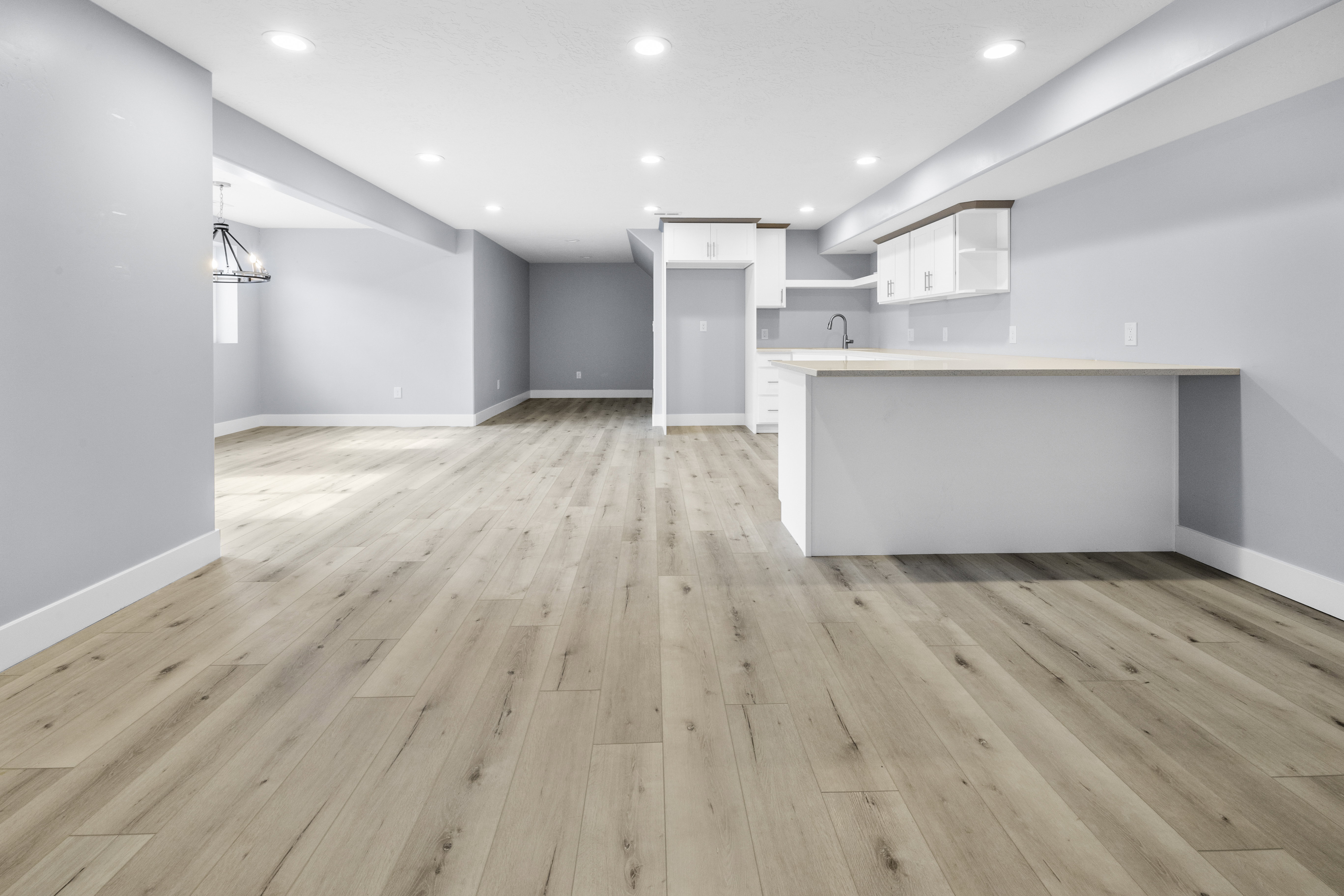 Open-concept living space featuring wood-finish flooring, recessed lighting, and a built-in wet bar with white cabinetry and a light-toned countertop