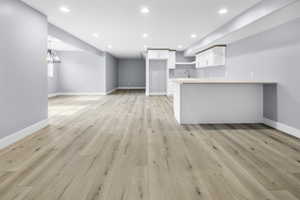 Open-concept living space featuring wood-finish flooring, recessed lighting, and a built-in wet bar with white cabinetry and a light-toned countertop