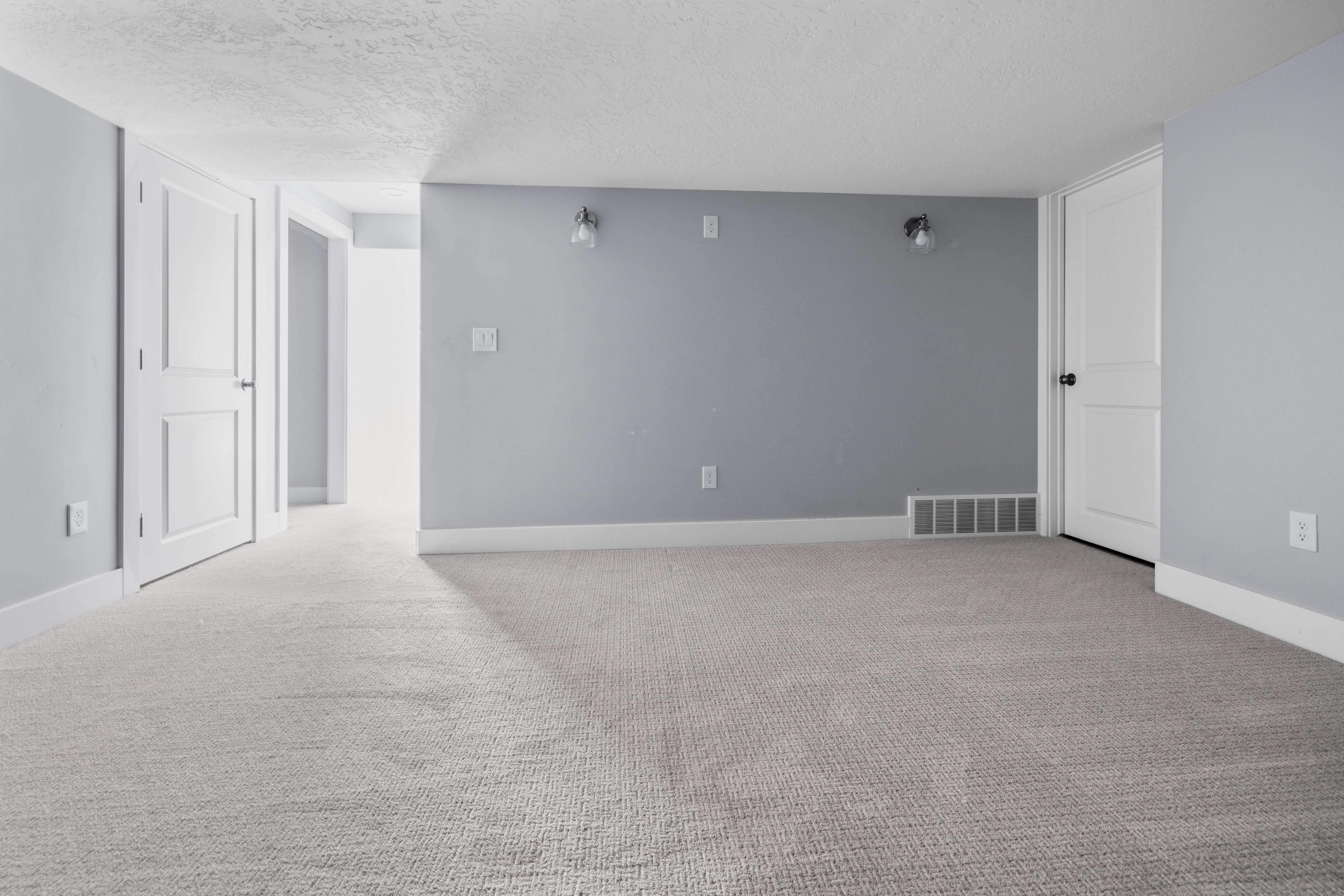 Carpeted room with light gray walls, white baseboards, and two paneled doors