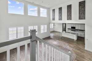 Two-story interior featuring a grand staircase with white spindles and a gray handrail, multiple large windows with white louvered shutters, and additional transom windows