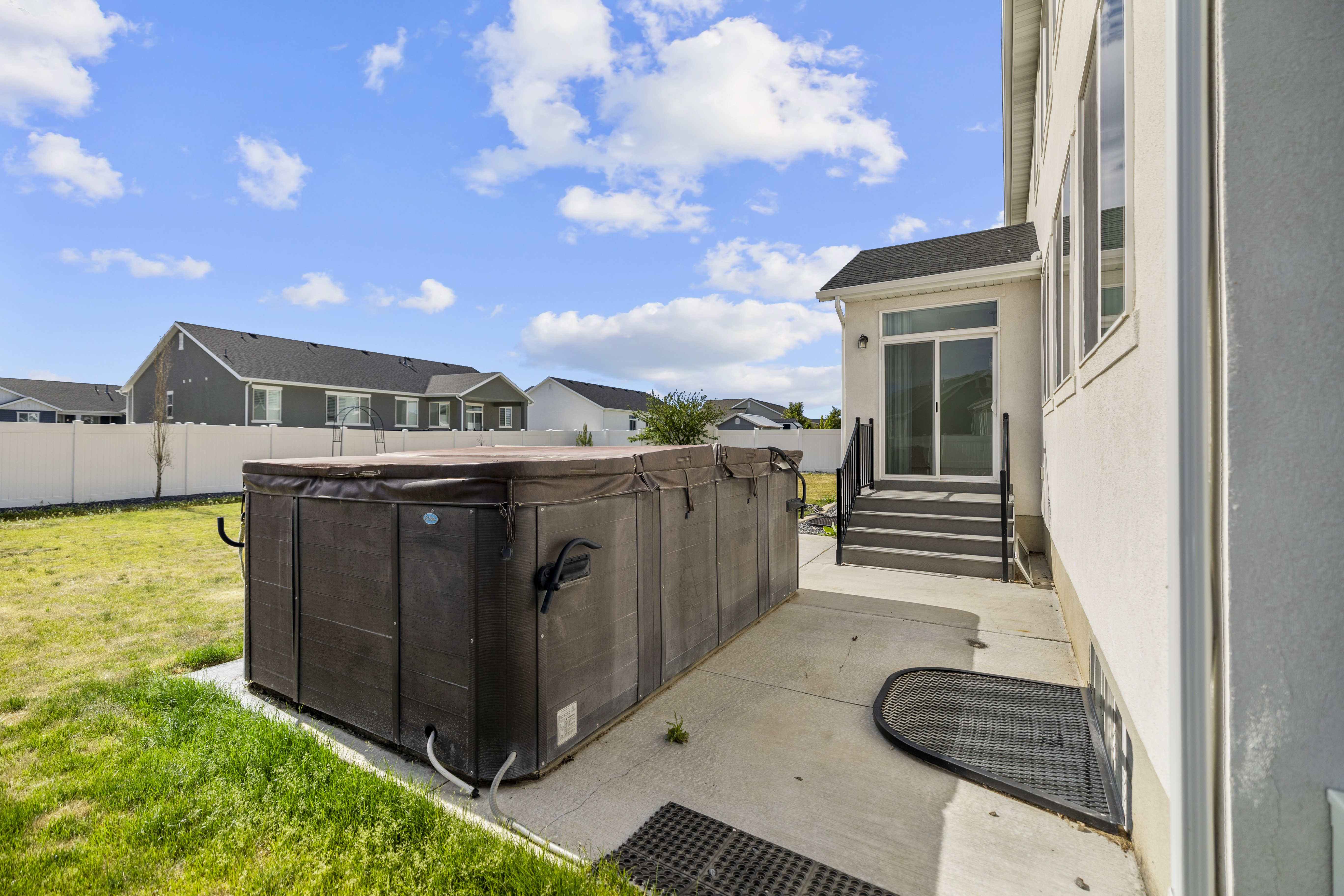 Spacious concrete patio featuring a hot tub/swim spa and direct access to the interior via sliding glass doors